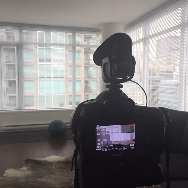 A photo of the back of a Cannon camera with a microphone on top of it.