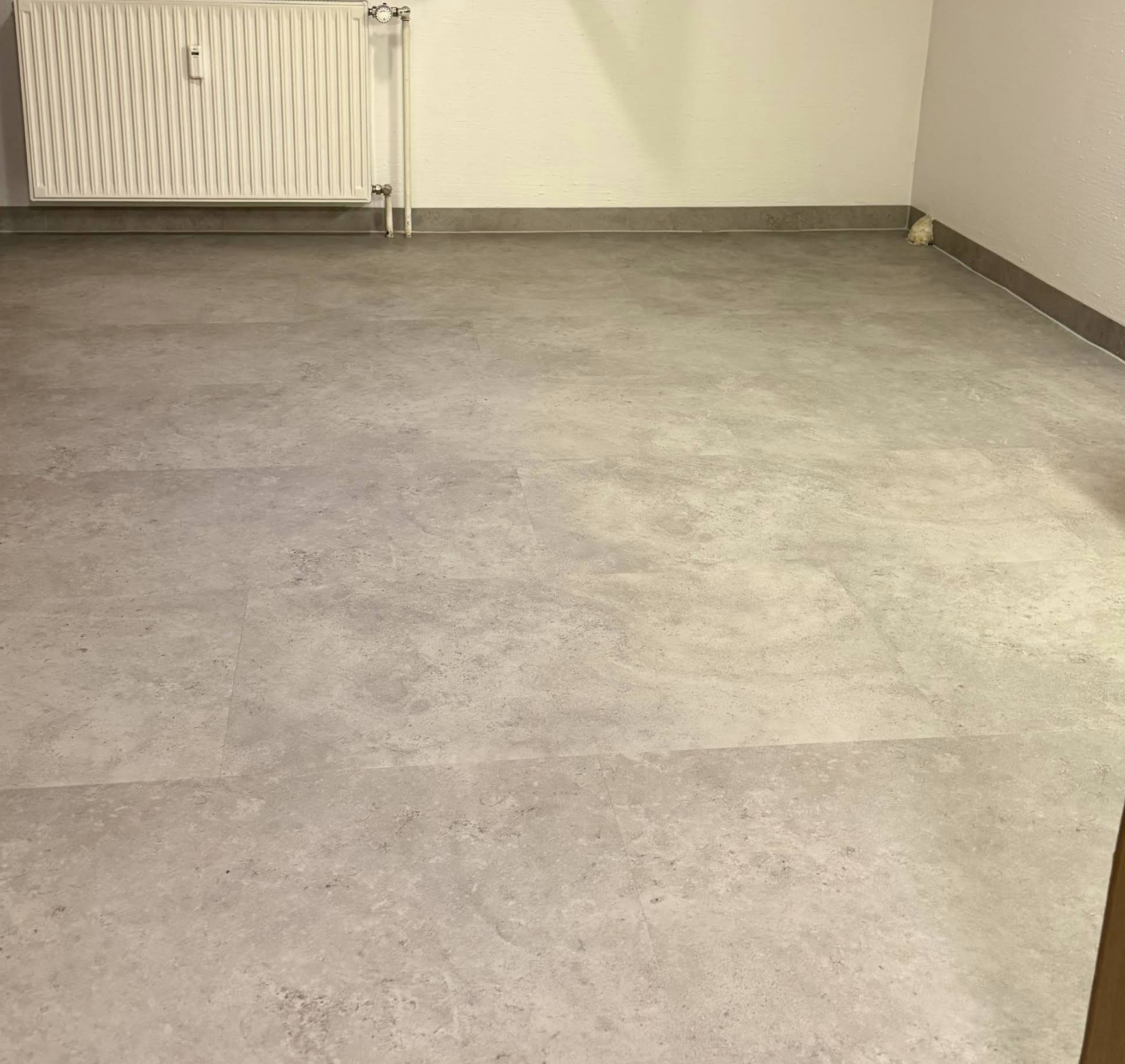 Moderner Vinylboden in Betonoptik mit passenden Sockelleisten, professionell verlegt durch die Schreinerei Holzbären in Fürth.