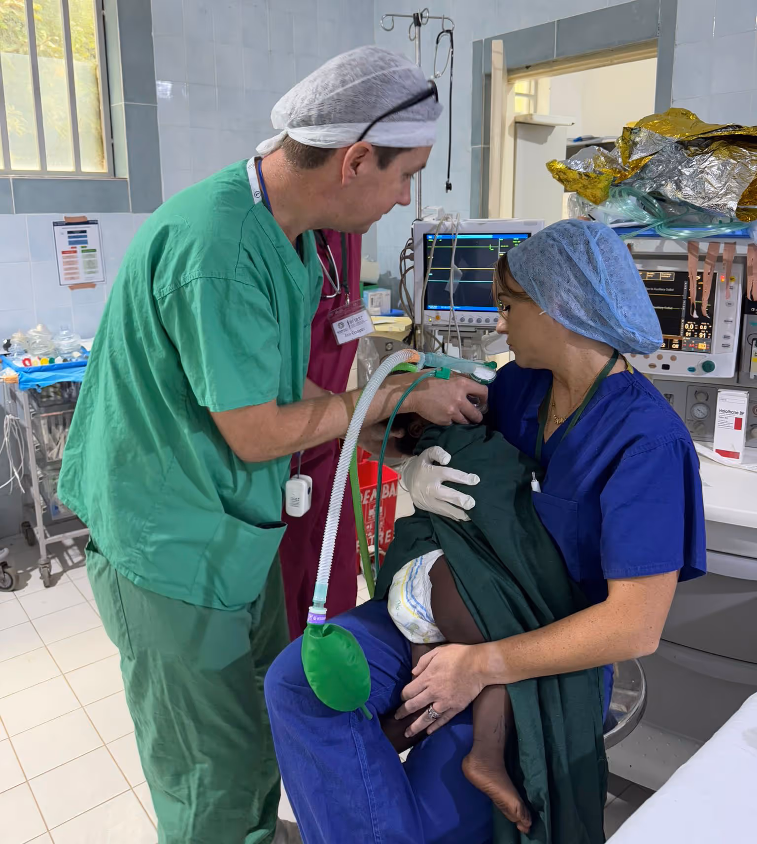 Two medical professionals examine a small child in a hospital, checking their condition with medical equipment.