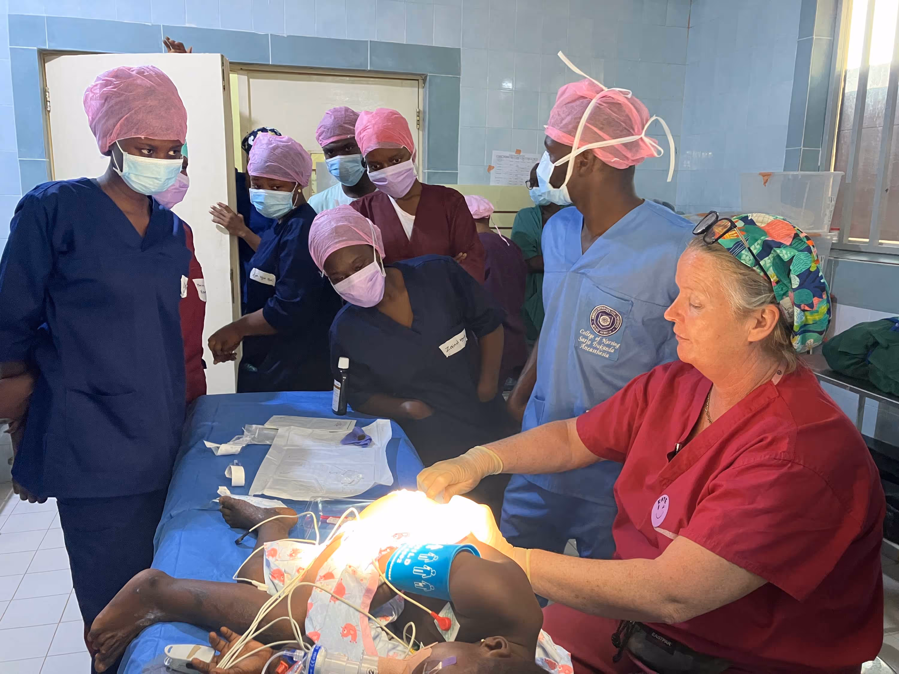 Medical staff perform a procedure on a child in an operating room, while others observe attentively.