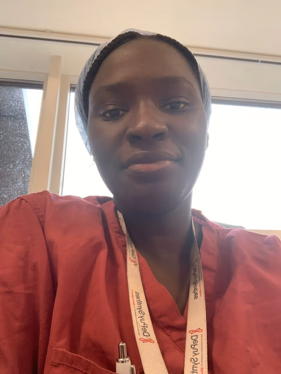 Person wearing a red shirt and lanyard, looking at the camera in an indoor setting.