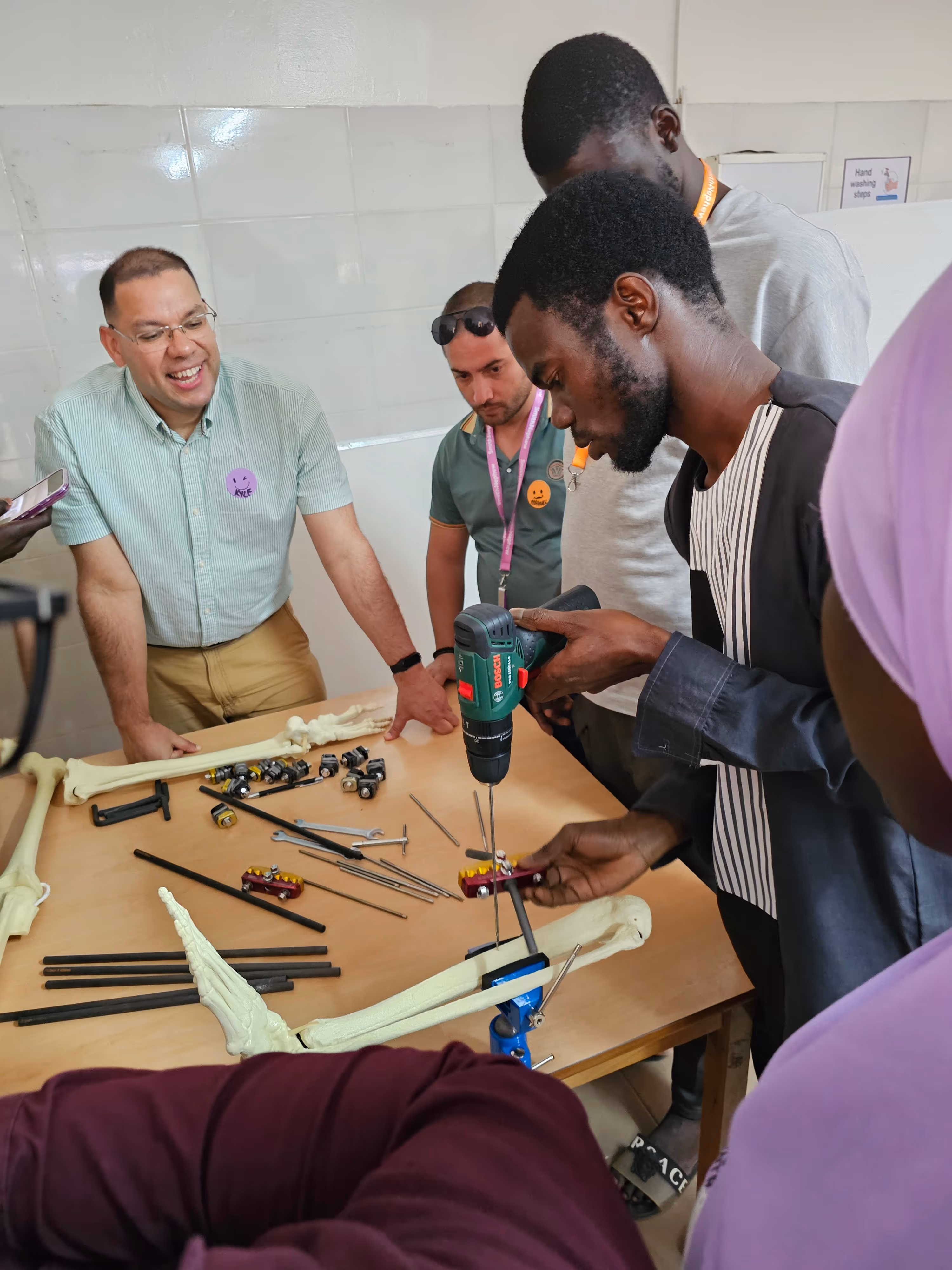 A group of people works together on a project using a drill and model bones.