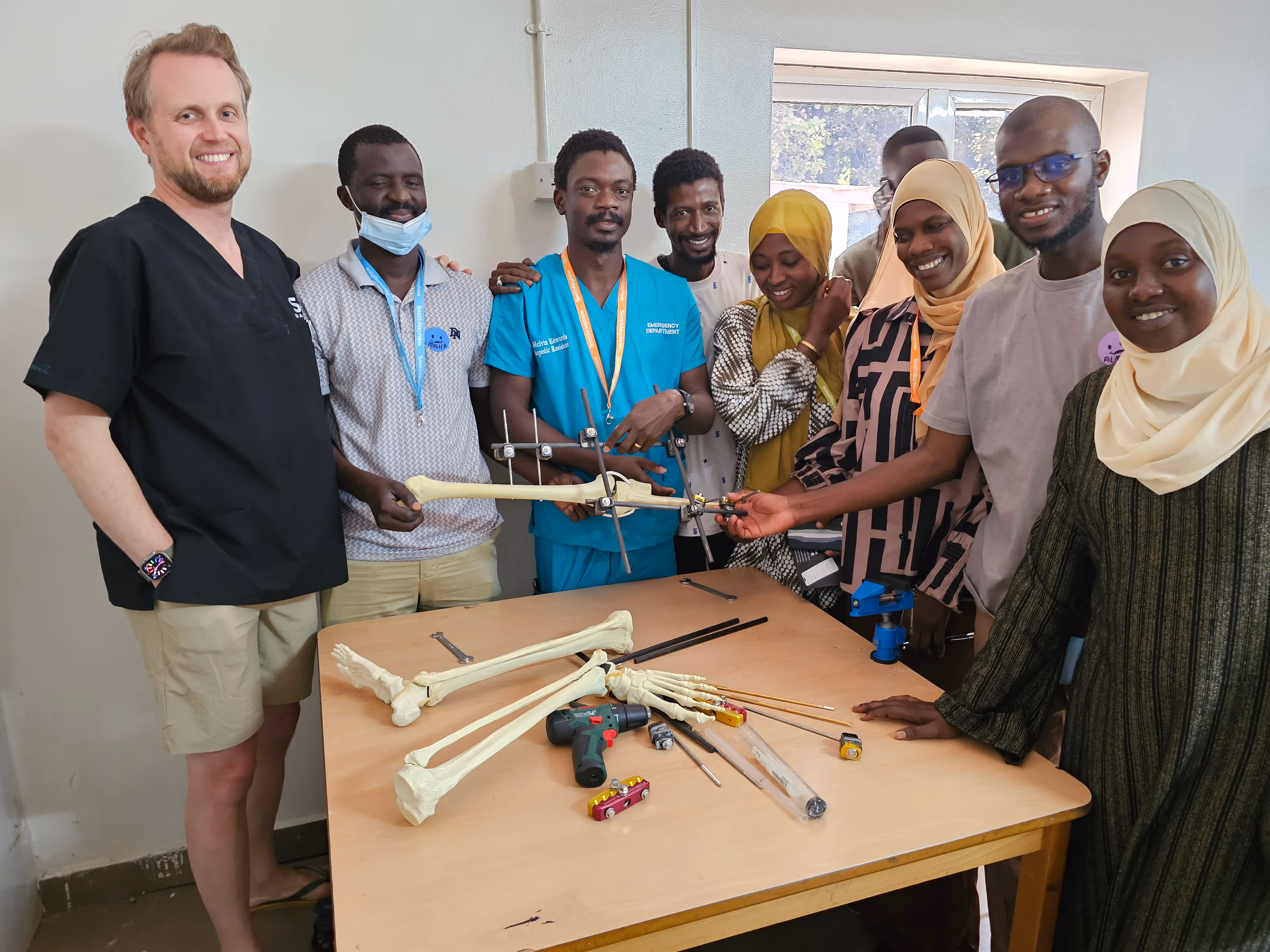 A group of people gathered around a table with skeletal models and medical tools, smiling at the camera.