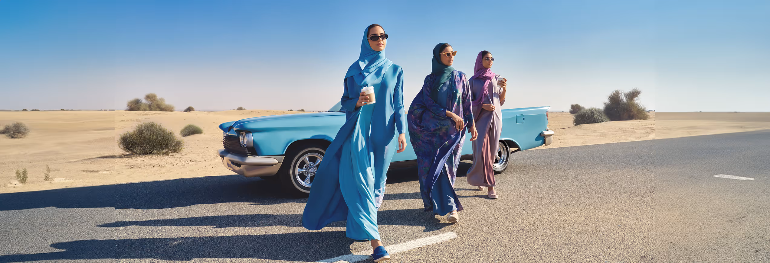 women in desert in front of blue vintage car
