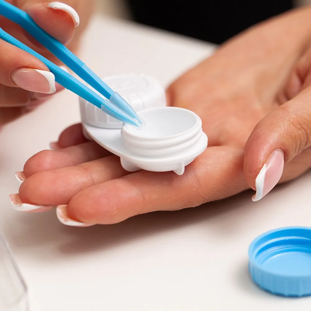 Blue tweezers placing sample into white container for medical testing