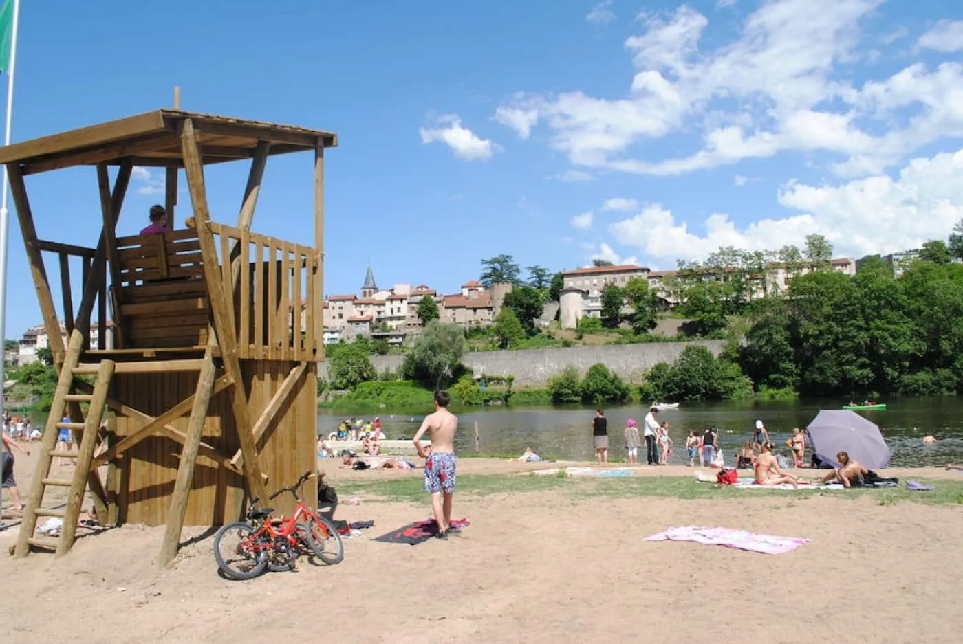 Plage aménagée en bord de Loire à Aurec-sur-Loire, avec maître-nageur et vue sur le village médiéval