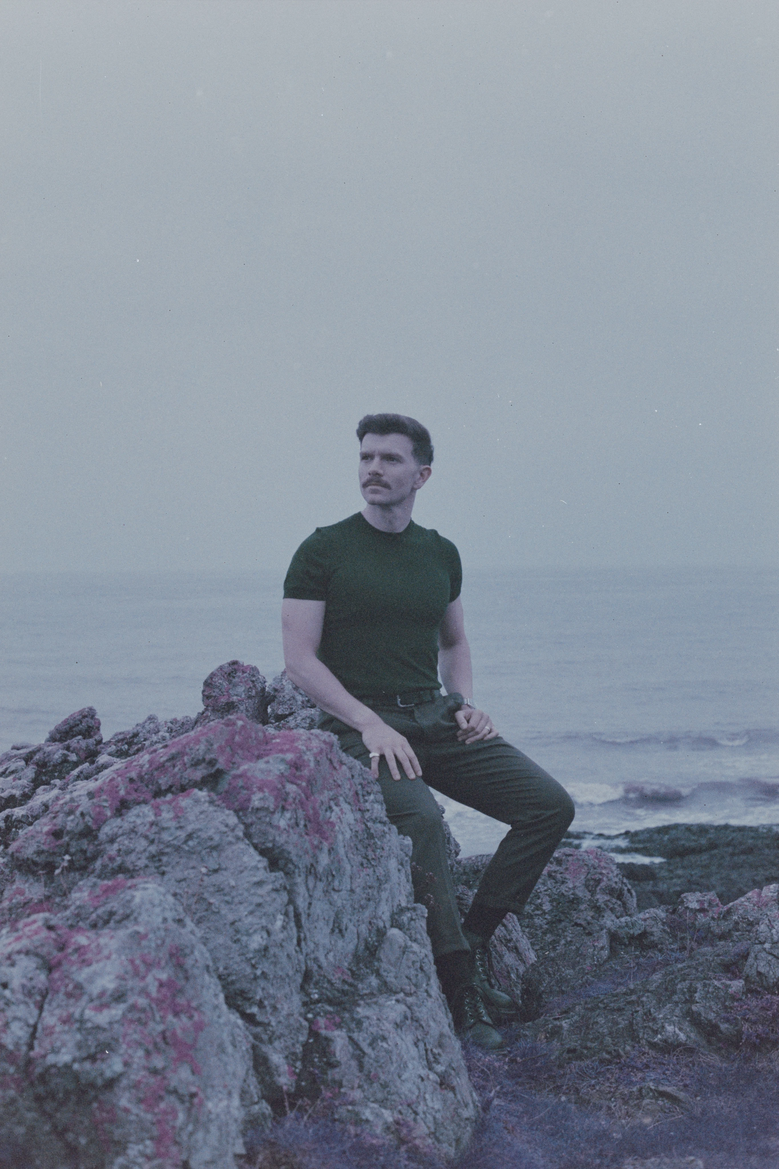 Andrew Gavin seated on coastal rocks by the sea
