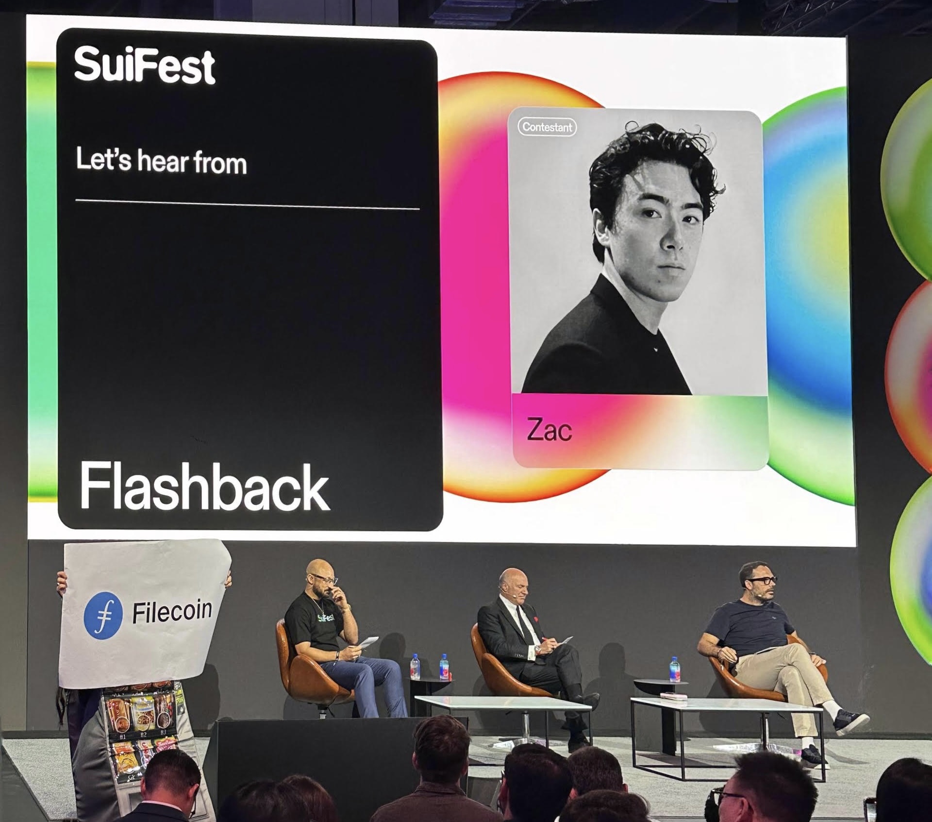Flashback Co-Founder Zac Steele presenting on stage at Sui Tank 2025 with judges Kevin O’Leary, Adeniyi Abiodun, and Kostas Chalkias.