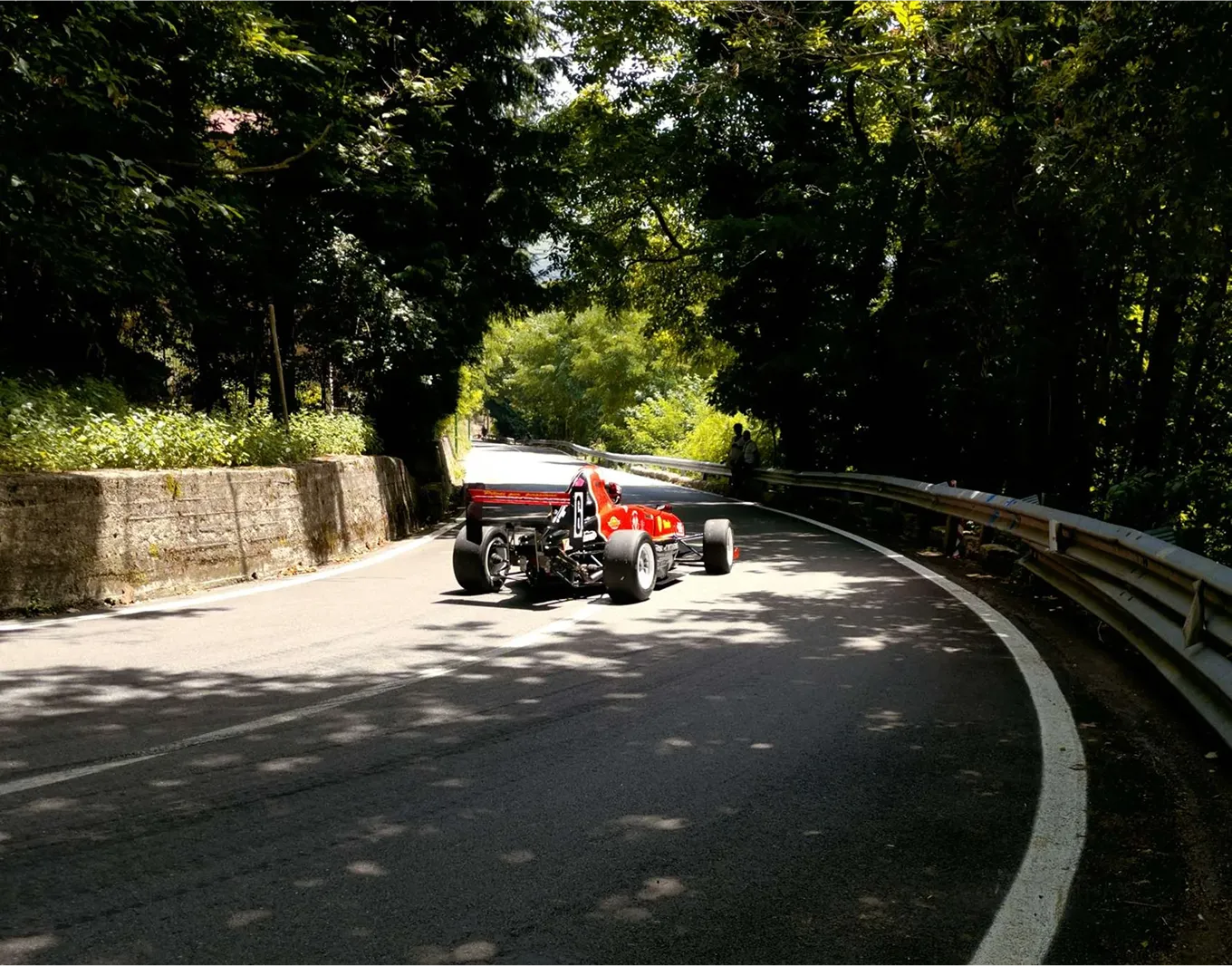 A car speeding on a road with trees around it.