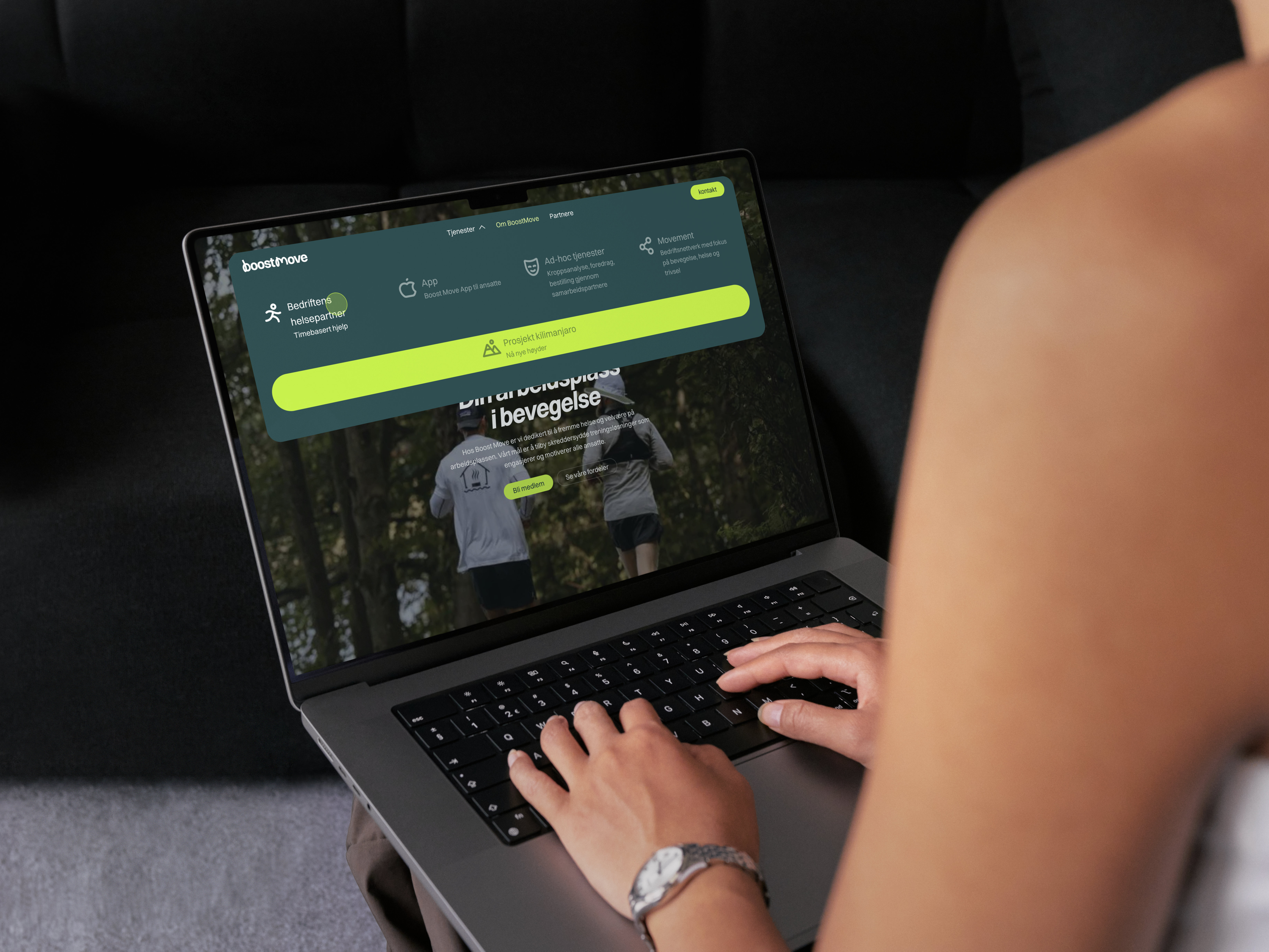 Person som skriver på en bærbar datamaskin med BoostMove-nettstedet åpent, som viser menyalternativer for bedriftshelsepartner, app, ad-hoc tjenester og movement.