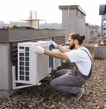 Technician servicing an air conditioner outdoor unit on a roof