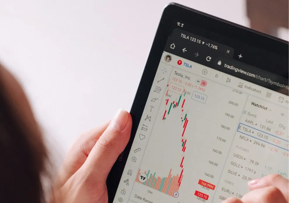 Person holding a tablet displaying Tesla stock chart on TradingView platform