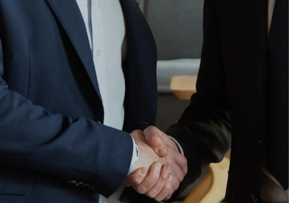 Close-up handshake between two business partners in formal suits, representing trust and partnership