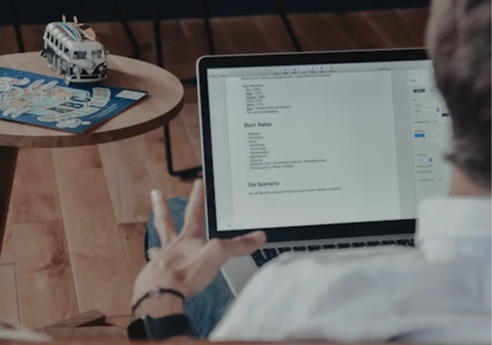 Businessman working on laptop with financial notes, symbolizing entrepreneurial planning and strategy