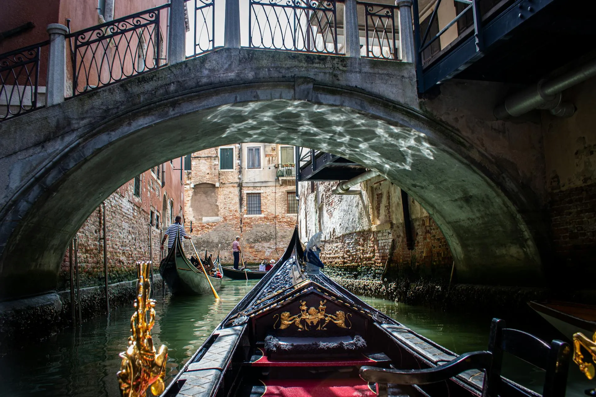 A gondola going under a bridge in venice.