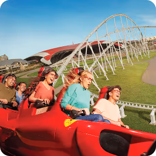 Group of people with safety goggles enjoying a ride in a red roller coaster on a sunny day.