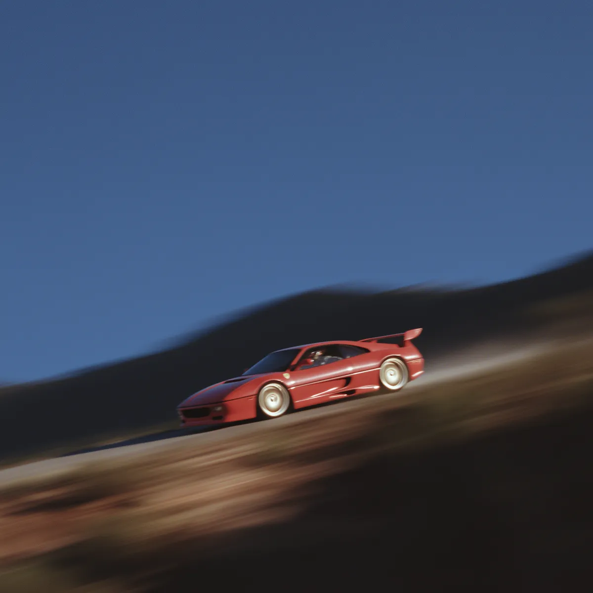 Red sports car speeding on a winding mountain road with blurred background.