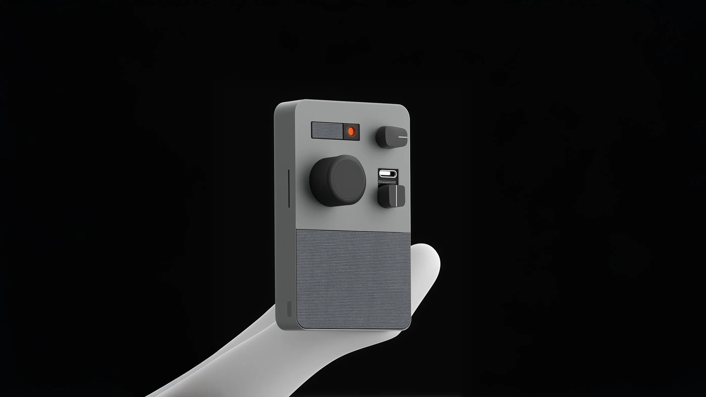 White hand holding a modern, compact gray device with multiple black knobs, a small screen, and textured speaker area against a black background.