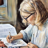 Woman with glasses writing or drawing at a desk.
