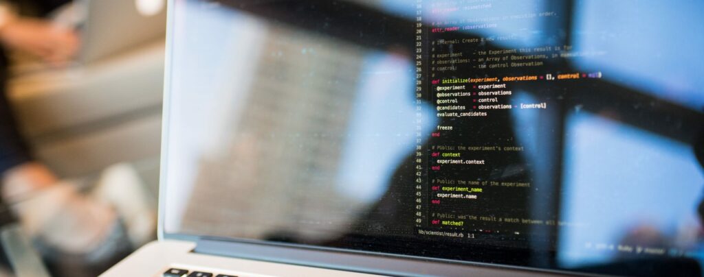 Photo of a laptop with a dark screen displaying lines of code.