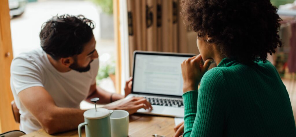 A man and a woman work on a laptop together 