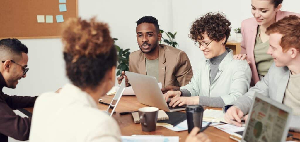 A photo of a group of people each working on laptops around a table.