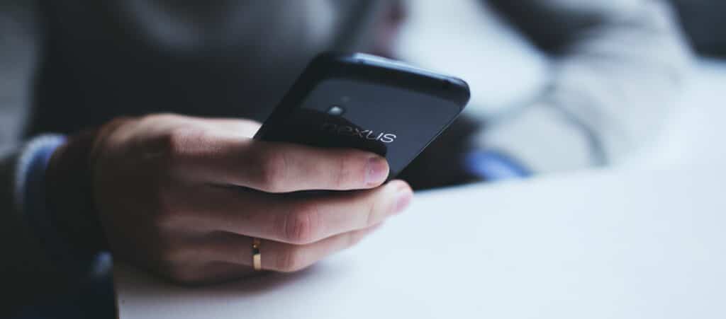 A photograph of someone's hand as they hold a smartphone.