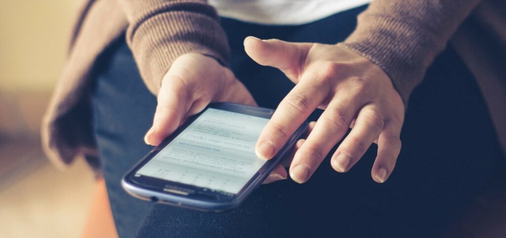 A close-up photo of someone scrolling on their smartphone.
