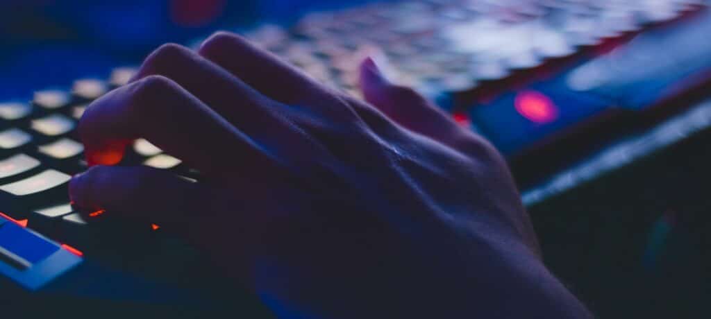 A close-up photograph of someone's typing hand in dim light