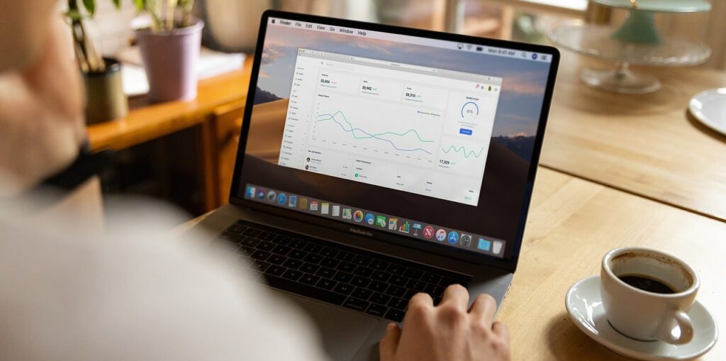 Someone types on their laptop while enjoying a cup of coffee.