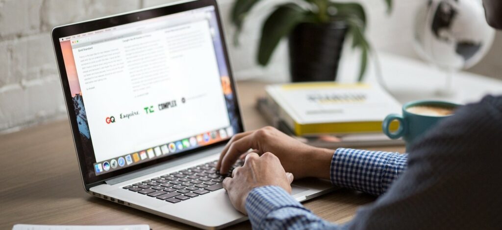A photograph of a man typing on a laptop.