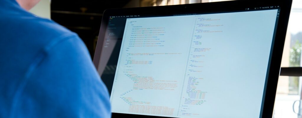 A photograph of a man looking at a computer monitor.