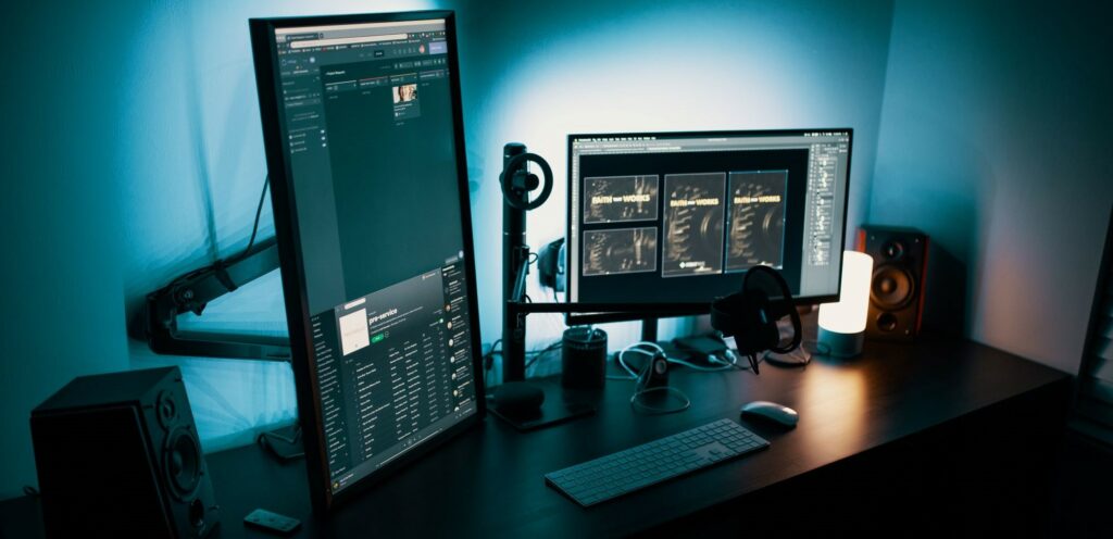 Two computer monitors at a dimly lit desk.
