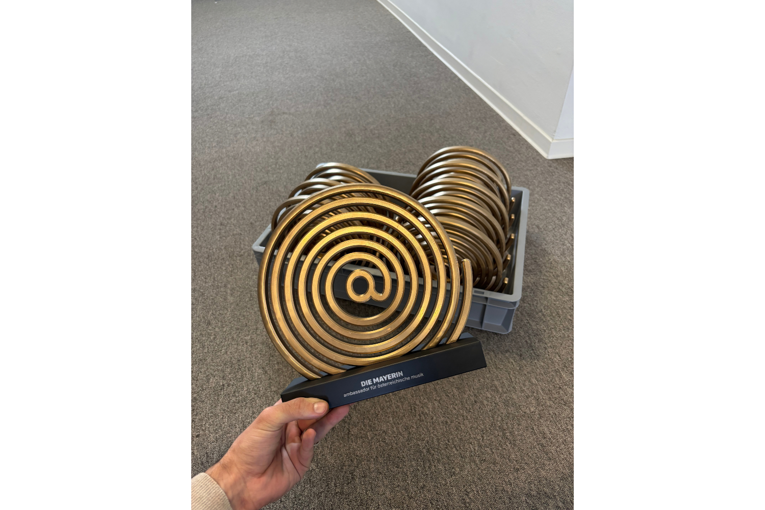 Award in der Hand vor einer Transportbox mit weiteren Awards
