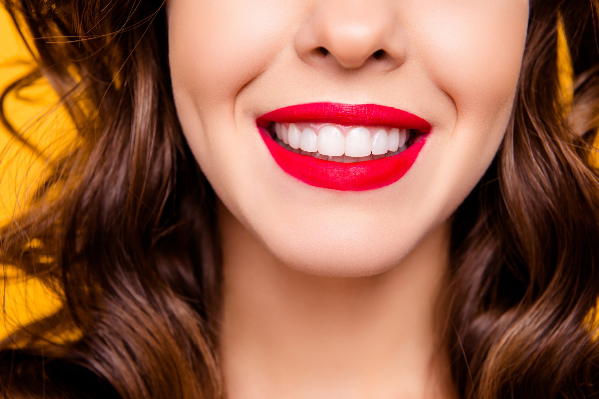 Close up half face portrait of toothy woman with beaming smile red lips white straight healthy teeth