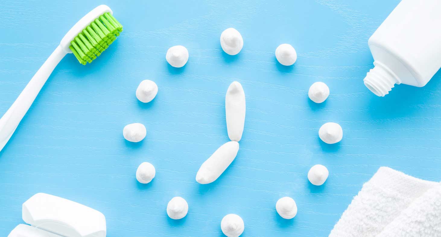 White toothpaste dots and lines form a clock reading seven o'clock, framed by a toothbrush and toopaste.