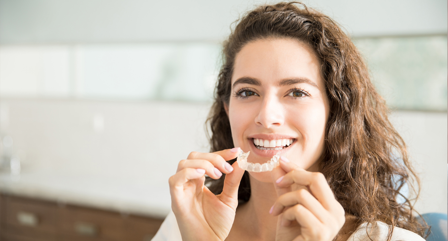 A female patient prepares to put her Invisalign aligner in.
