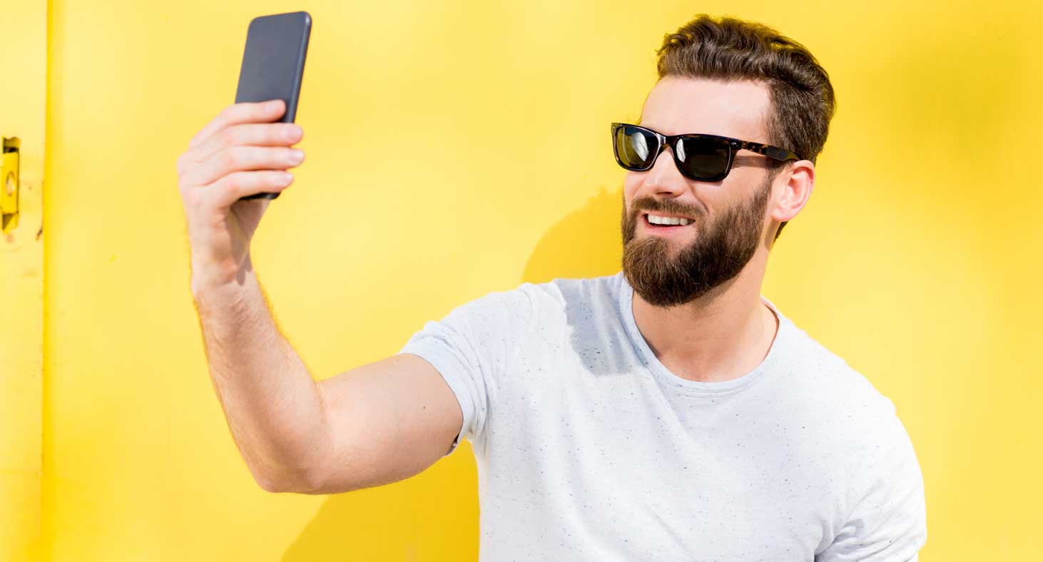 A man takes a selfy on his phone to document his professional teeth whitening by a Little Rock dentist.