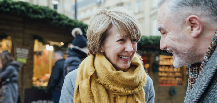 An older Little Rock, AR woman and man smile at each other, showing their mini dental implants to be unidentifiable from their teeth.