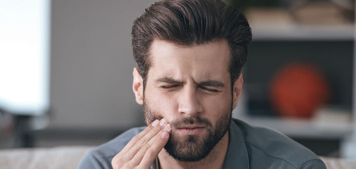 A patient rubs his cheek, in need of an emergency cavity filling in Little Rock, AR.