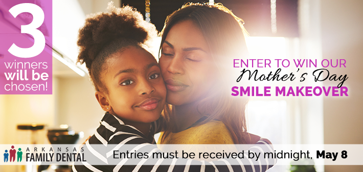 A mother and her young daughter hug each other behind an advertisement for a mother's day makeover contest.