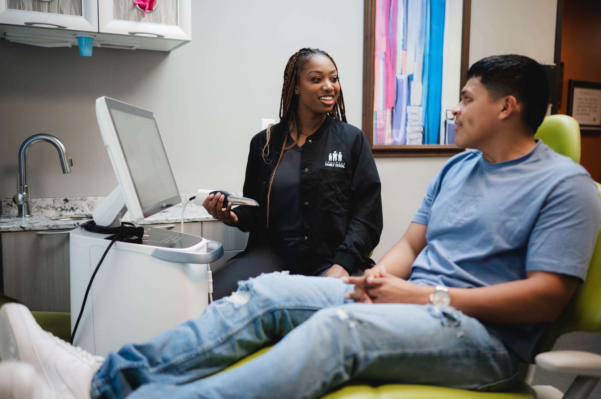  A female dentist smiling as she explains the process of same day crowns to a male patient
