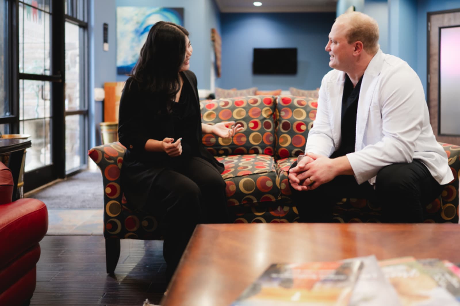 A dentist discusses treatment options with a patient in a modern dental office consultation area.