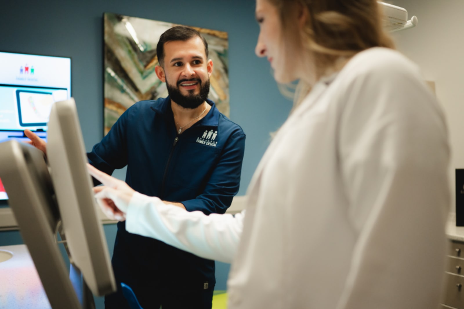 Dentist consulting with patient in treatment room using computer display
