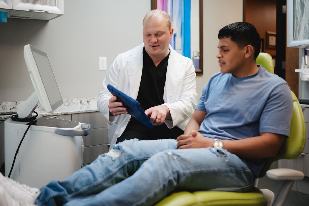 Dentist explaining dental implant model to patient in treatment room