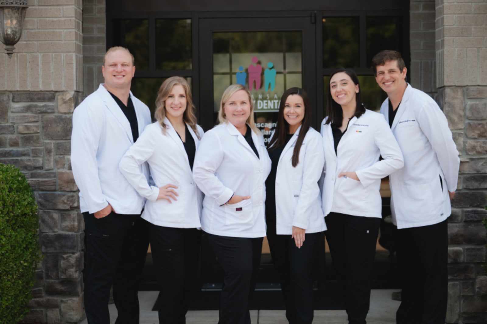 Arkansas Family Dental team in white coats standing outside brick building