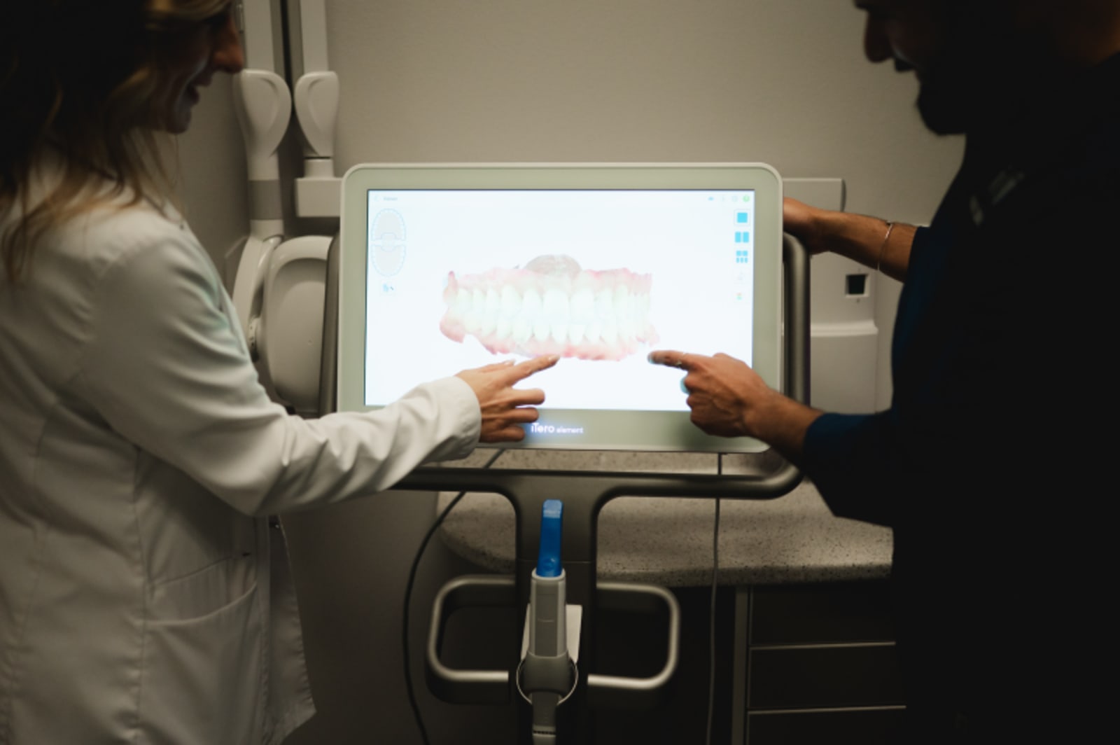 Dental professional reviewing digital scan on tablet with patient
