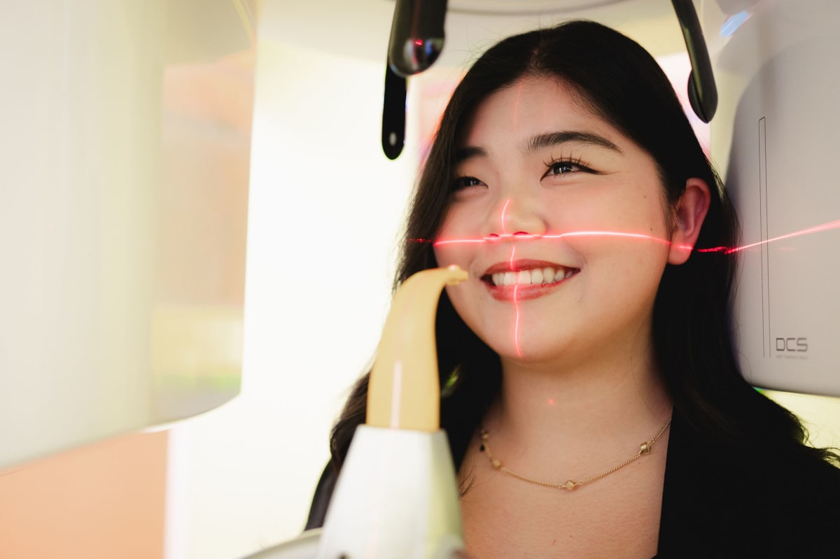 Woman smiling during a dental examination wearing protective eyewear at Arkansas Family Dental