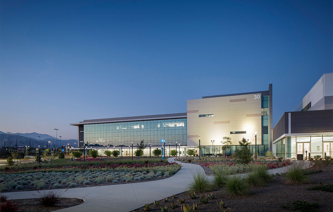 Modern glass building with landscaped grounds at sunset or sunrise
