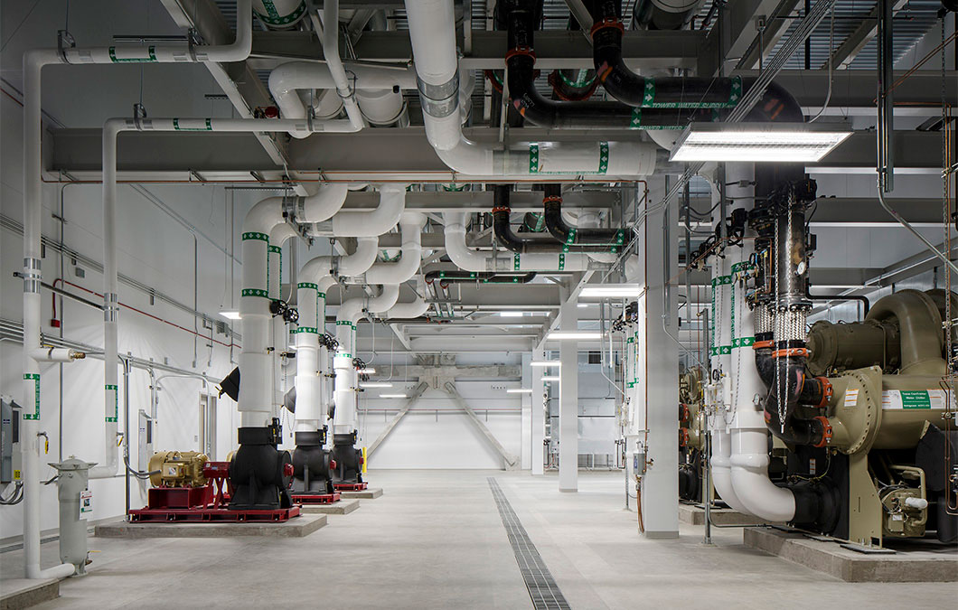 Industrial mechanical room with complex white piping and large machinery